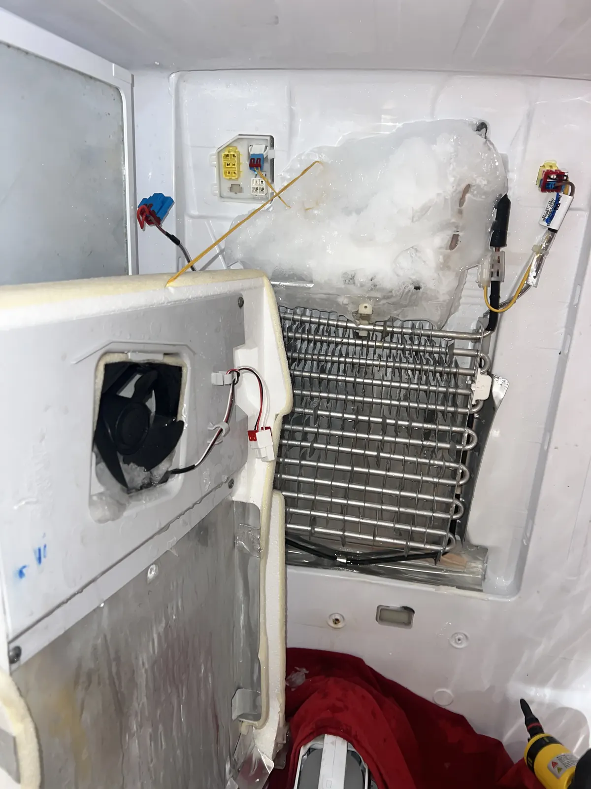 Refrigerator repair — evaporator fan panel removed to reach the fault